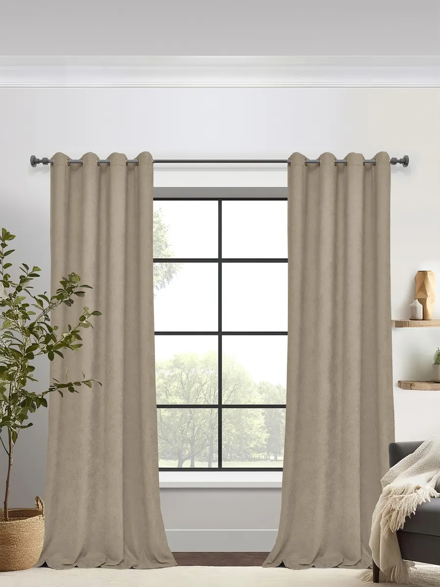 Modern sage grommet curtains elegantly frame a black-framed window, softly diffusing natural light in a minimalist living room with a potted plant and wooden shelves.