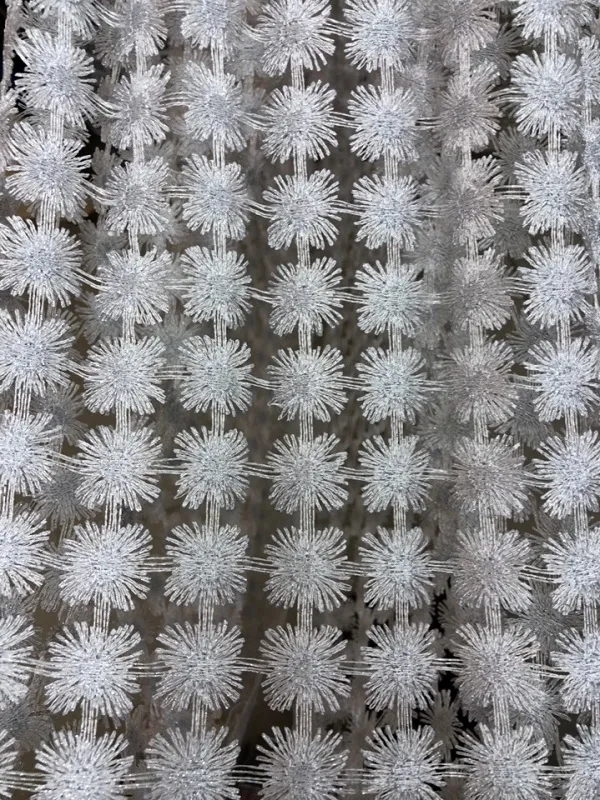 Светлая сетчатая штора с узором из снежинок висит на окне, пропуская рассеянный дневной свет, создаёт ощущение воздушности и утончённости в просторной светлой комнате.