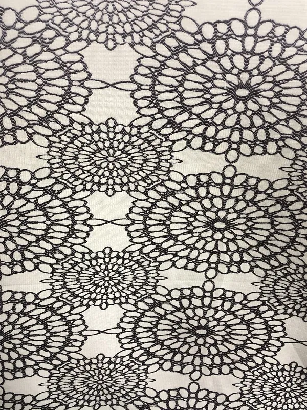 Комплект штор с кружевным узором висит на окне, мягко рассеивая дневной свет. Интерьер выглядит утончённо и романтично, с нежным оттенком ткани и игрой света на узоре. В комнате тёплый уютный свет, создающий атмосферу спокойствия и изысканности.