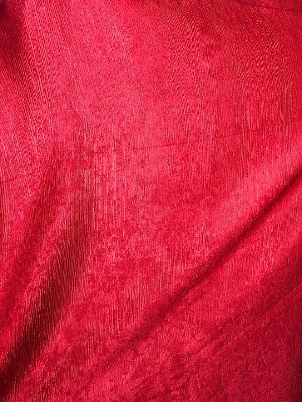 Тяжёлая красная штора с выраженной фактурой висит на окне, мягко отбрасывая тени. В комнате тёплый вечерний свет, создающий уютную и роскошную атмосферу.