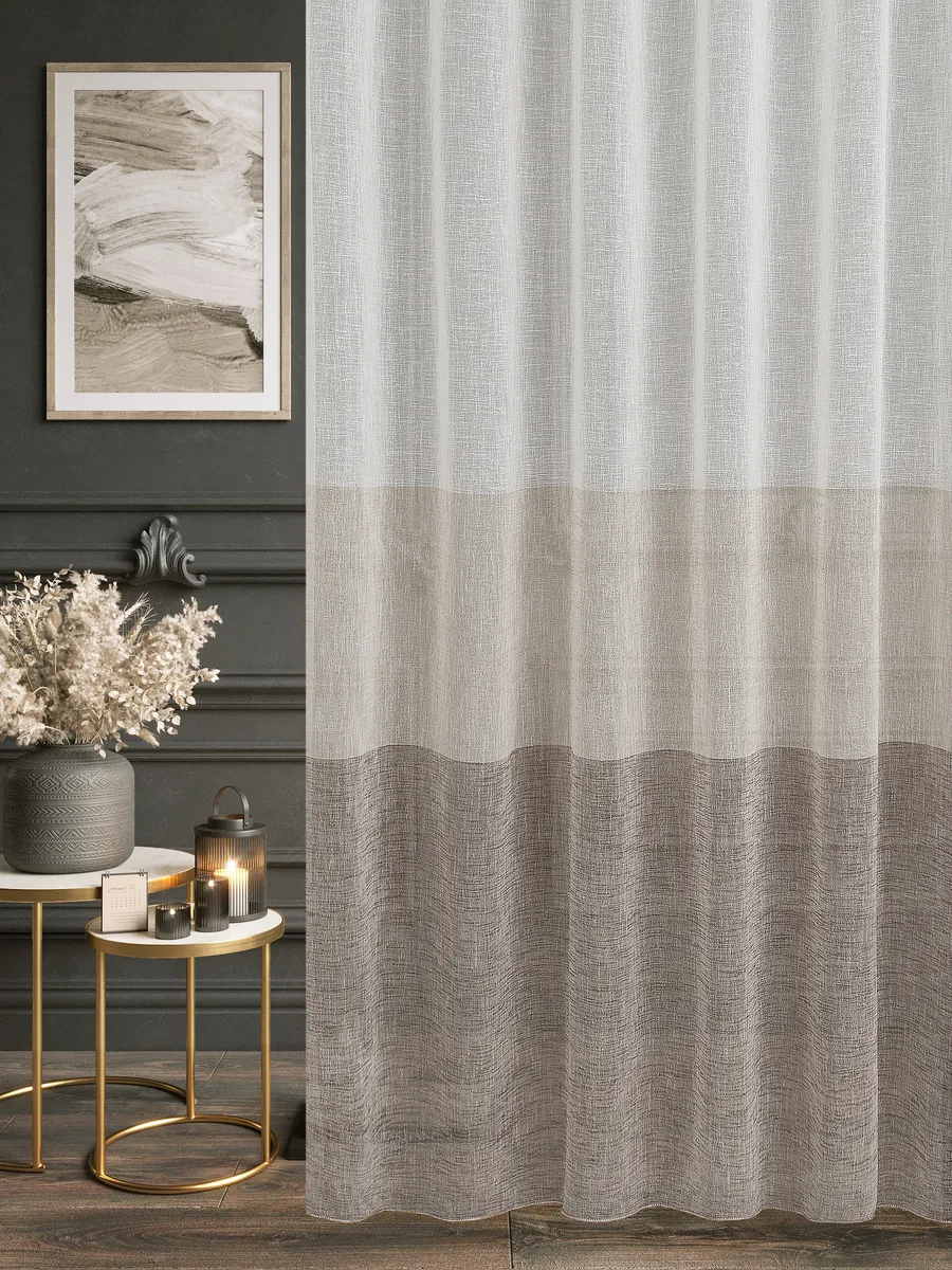 Лёгкий тюль с градиентом от светлого бежевого к тёплому серо-бежевому, висит на окне в уютной комнате с тёмными стенами, золотыми столиками и сухими цветами. Свет мягко проникает сквозь ткань, создавая рассеянное утро. Интерьер в стиле лофта с акцентами на текстурах и приглушённых тонах.