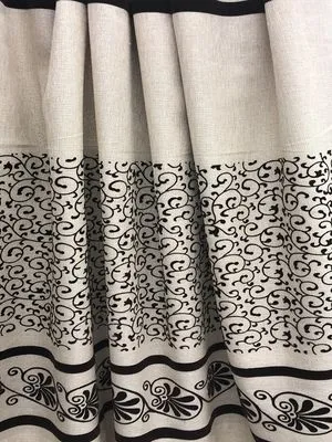 Luxurious ivory linen curtains with intricate black scrollwork patterns, softly draped to highlight elegant folds and timeless interior design.