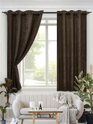 Modern espresso velvet curtains with grommets elegantly draped over a large window, softly filtering daylight in a minimalist living room with white sofa and green plants.