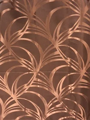 Copperleaf Whisper Sheer curtains with delicate leaf patterns, softly draped in natural light, creating a warm, airy ambiance in a modern living space.