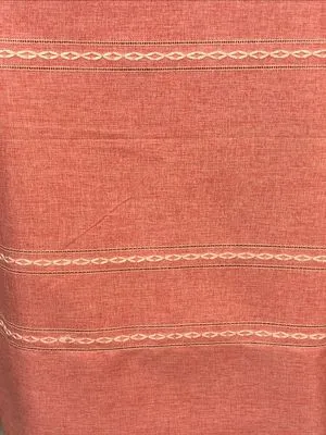 Terracotta linen drape with delicate hemstitch detailing, softly draping in natural light, evoking rustic elegance and warm, earthy tones in a serene interior setting.