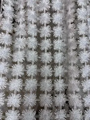 Светлая сетчатая штора с узором из снежинок висит на окне, пропуская рассеянный дневной свет, создаёт ощущение воздушности и утончённости в просторной светлой комнате.