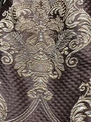 Тяжёлая штора с золотистым вензелем висит на окне, мягкий свет падает на узор, создаёт атмосферу роскоши и уюта в классическом интерьере.