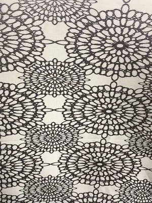 Комплект штор с кружевным узором висит на окне, мягко рассеивая дневной свет. Интерьер выглядит утончённо и романтично, с нежным оттенком ткани и игрой света на узоре. В комнате тёплый уютный свет, создающий атмосферу спокойствия и изысканности.