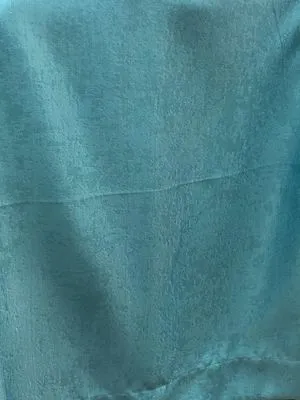 Текстиль с рельефной фактурой в синих тонах висит на окне, мягкий дневной свет проходит сквозь него, создавая уютную атмосферу в спальне.