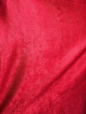 Тяжёлая красная штора с выраженной фактурой висит на окне, мягко отбрасывая тени. В комнате тёплый вечерний свет, создающий уютную и роскошную атмосферу.